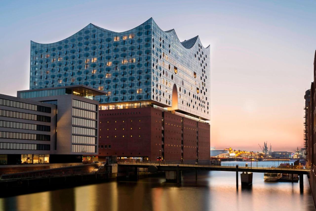 The Westin Hamburg Elbphilharmonie Hotel Luaran gambar The photo shows a modern architectural structure located by a body of water, possibly a river or canal. The building features a unique wavy roofline and a facade made of glass and other materials, giving it a contemporary look. It is likely a cultura
