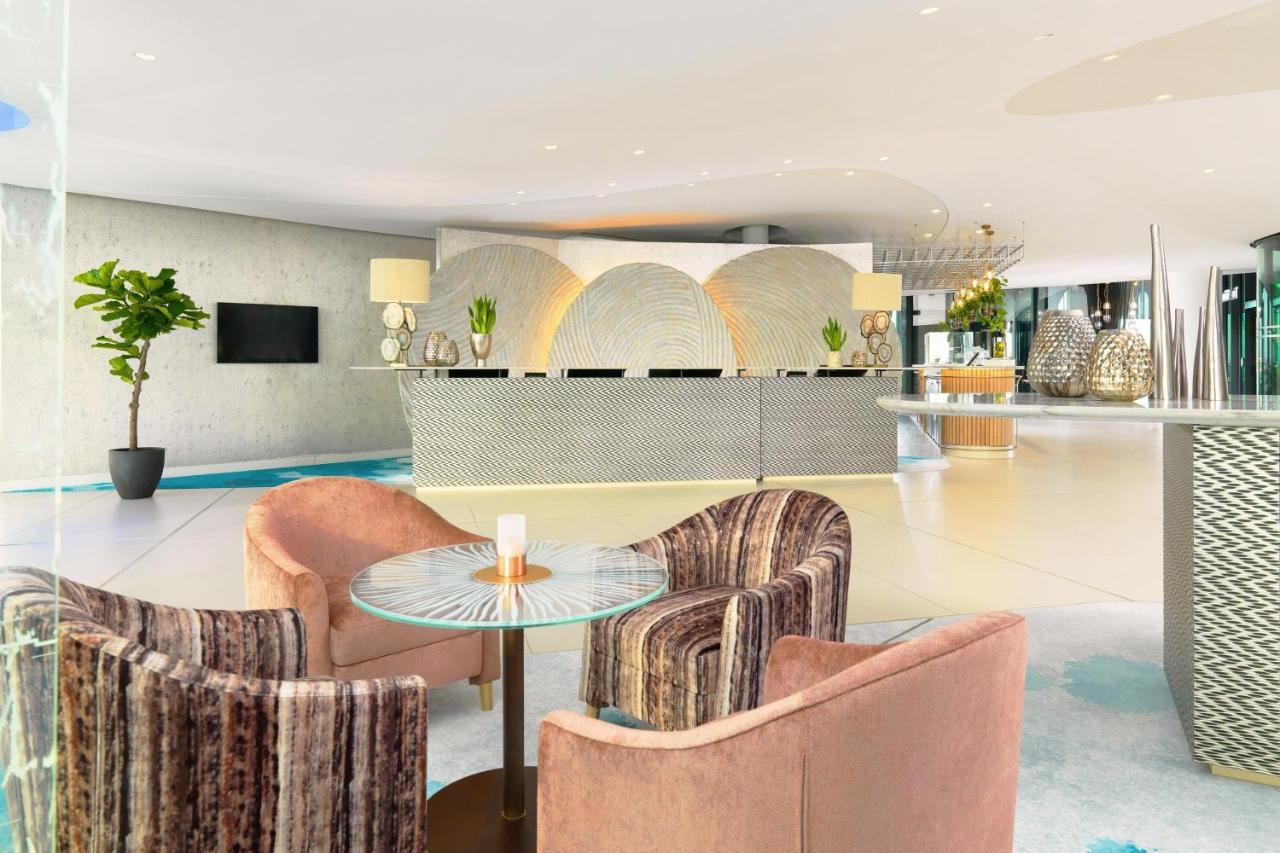 The Westin Hamburg Elbphilharmonie Hotel Luaran gambar The photo shows a modern hotel lobby with a stylish reception area. The reception desk has a sleek, contemporary design and is centered against a light-colored wall featuring abstract patterns. 

In front of the desk, there are two sets of seating ar