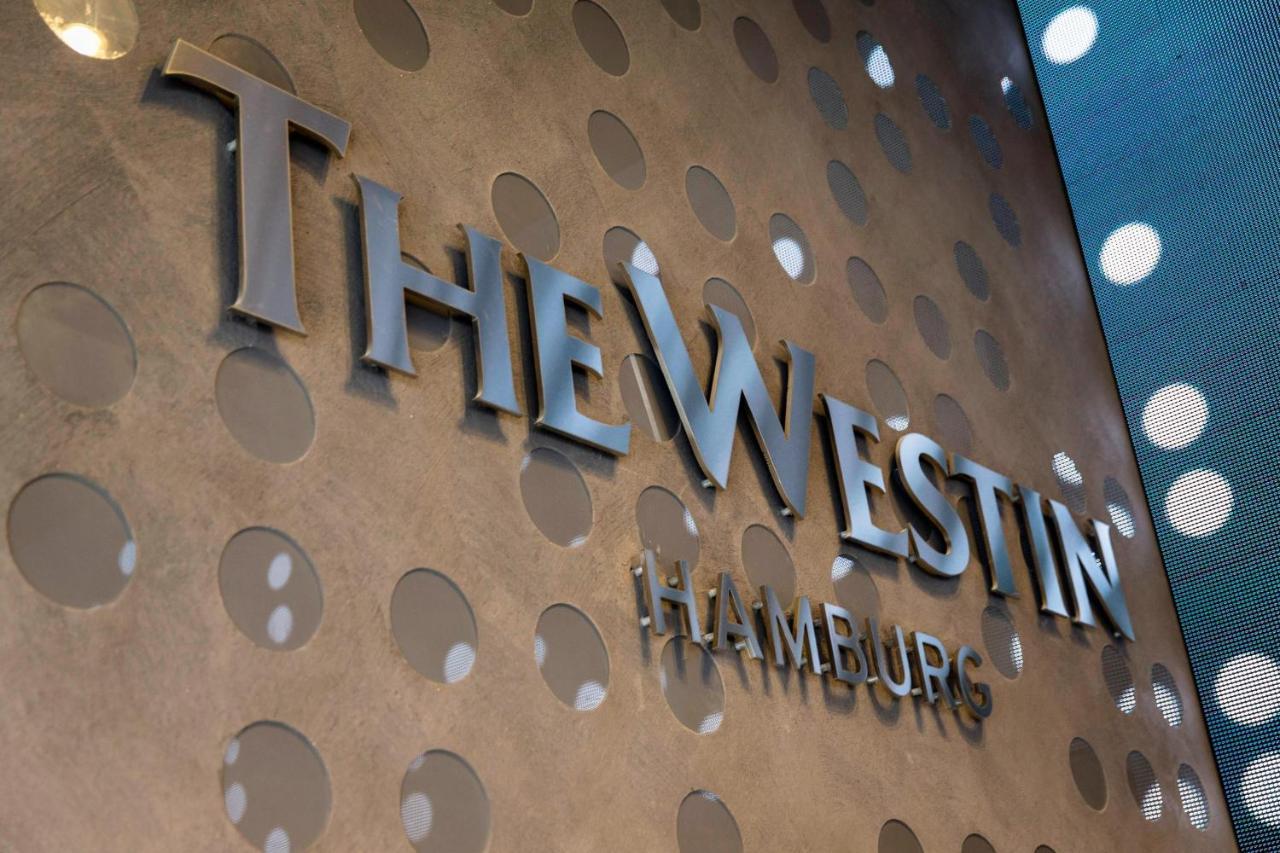 The Westin Hamburg Elbphilharmonie Hotel Luaran gambar The image shows a decorative wall featuring the logo of "The Westin Hamburg." The logo is prominently displayed in a sleek, silver font. The background has a textured surface with circular patterns, adding a modern and elegant touch to the overall ap