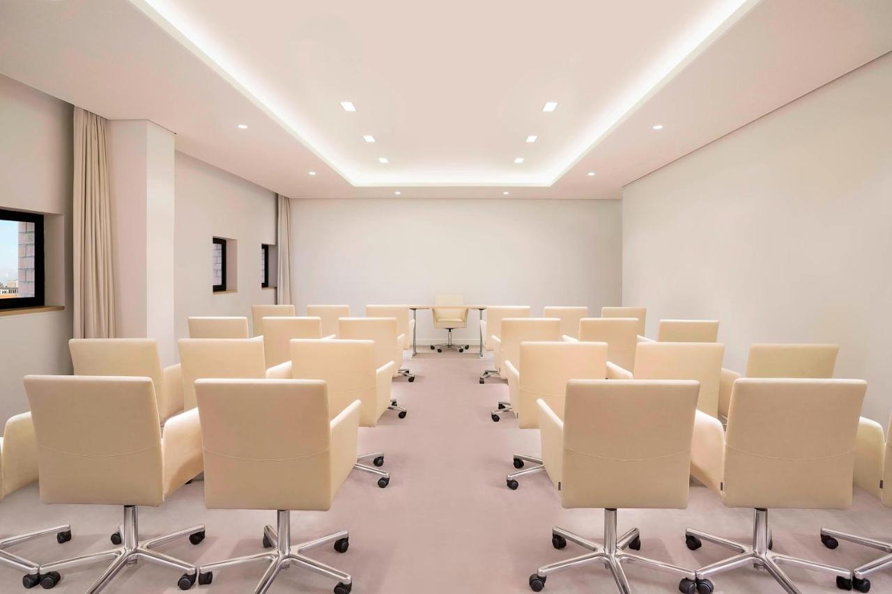 The Westin Hamburg Elbphilharmonie Hotel Luaran gambar The photo shows a modern conference room. There are several light-colored, wheeled chairs arranged in rows facing a central area where a glass table is located. The room has soft lighting from recessed ceiling lights, and the walls are mostly white, 