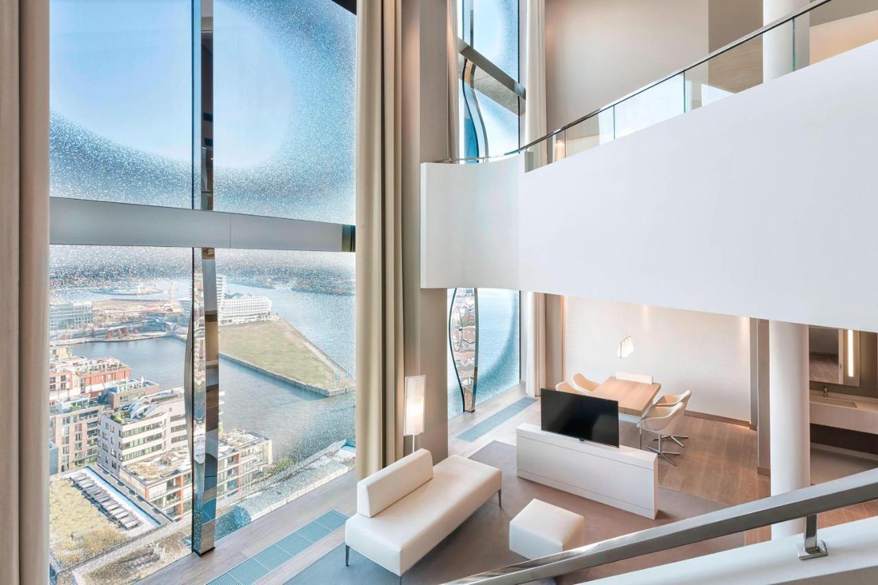 The Westin Hamburg Elbphilharmonie Hotel Luaran gambar The photo showcases a modern, stylish interior of a multi-level living space. It features large, floor-to-ceiling windows that provide a panoramic view of the surrounding landscape and water. The decor is minimalist, with a predominantly white color 