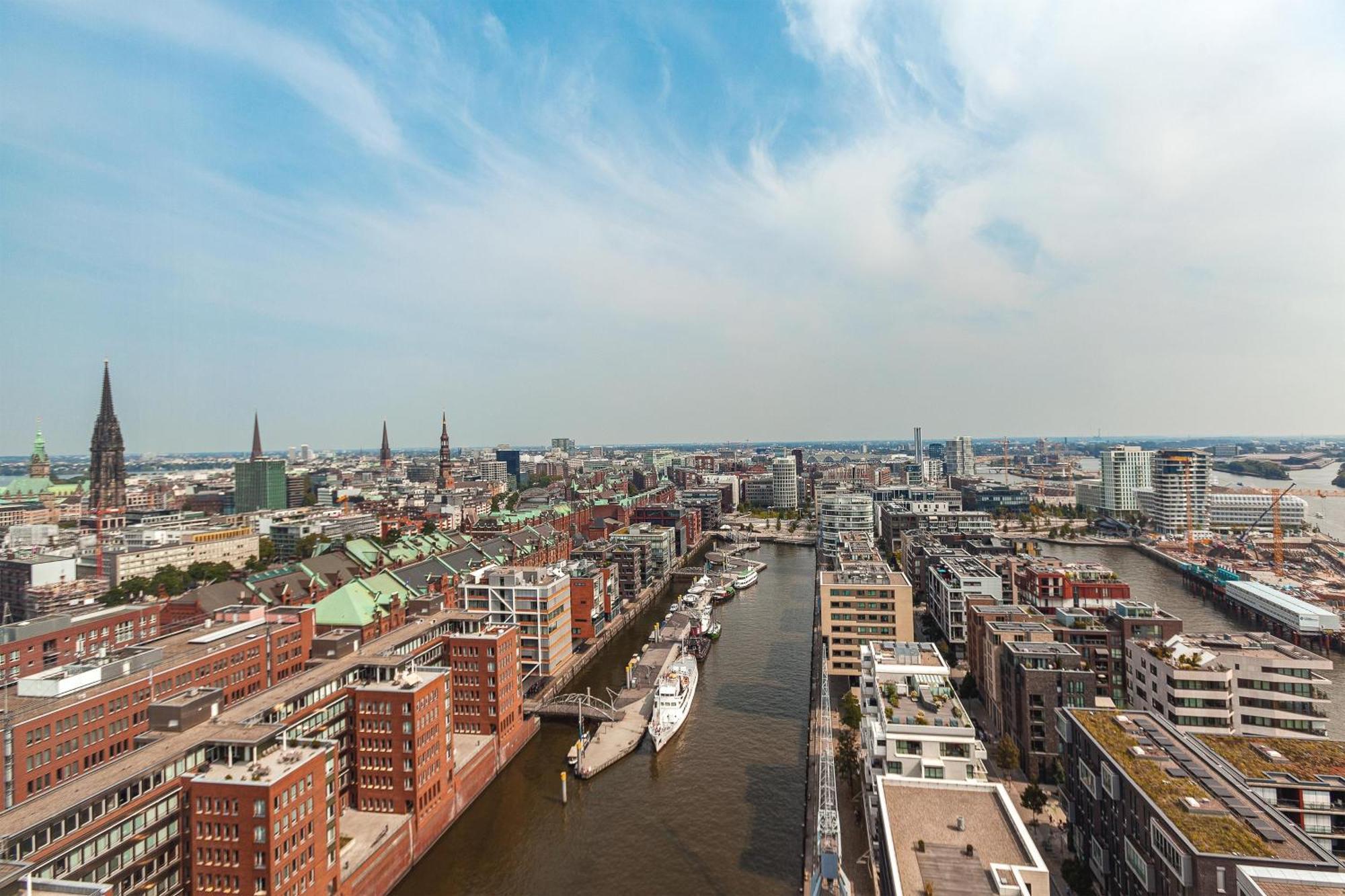 The Westin Hamburg Elbphilharmonie Hotel Luaran gambar The photo shows an aerial view of a cityscape with a prominent waterfront area. There are modern and historic buildings lining both sides of a river or canal, suggesting an urban environment. The architecture appears diverse, with a mix of contempora